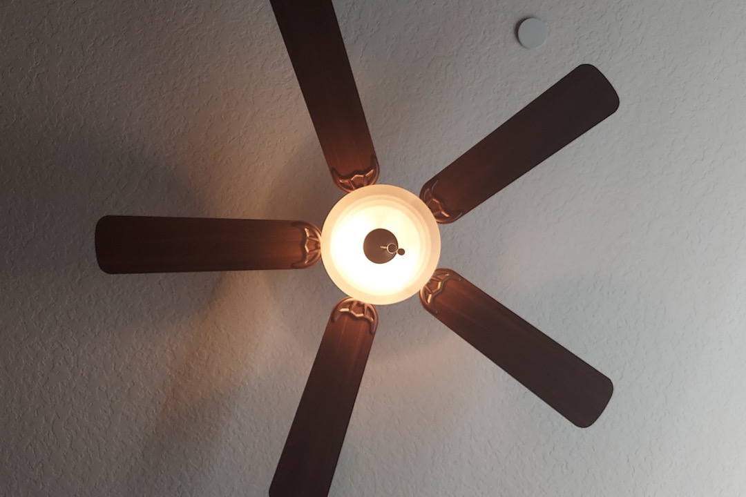White ceiling fan with wooden blades mounted on a living room ceiling