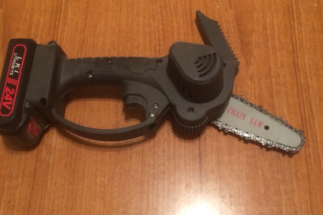 Cordless battery-powered chainsaw cutting a log on a residential property