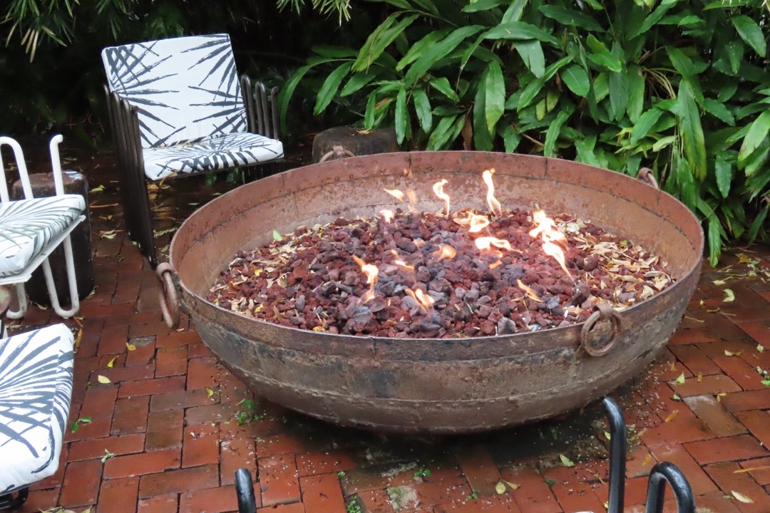 Lit backyard fire bowl burning wood on a patio at dusk