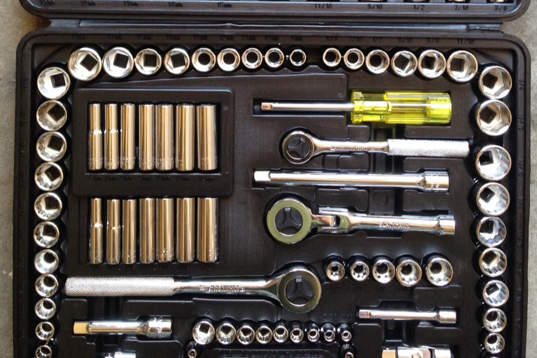 Mechanics tool set with sockets, ratchets, and combination wrenches in an organized case