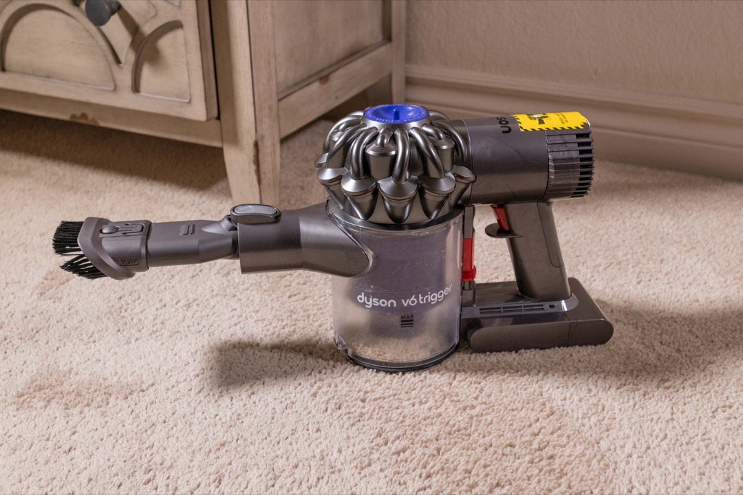Handheld cordless vacuum cleaning sawdust off a workbench surface