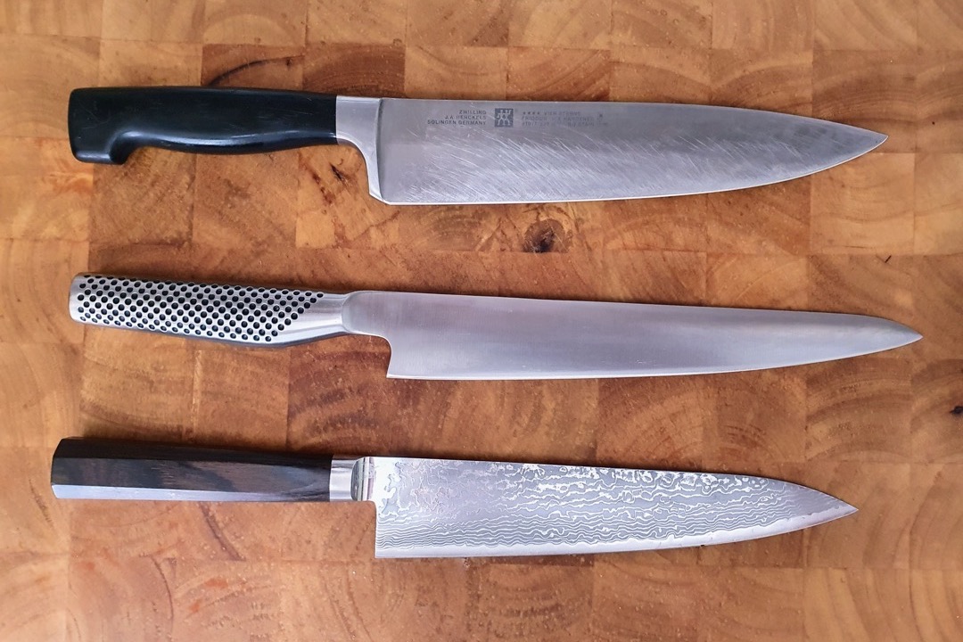 Professional chef's knife with stainless steel blade on a wooden cutting board
