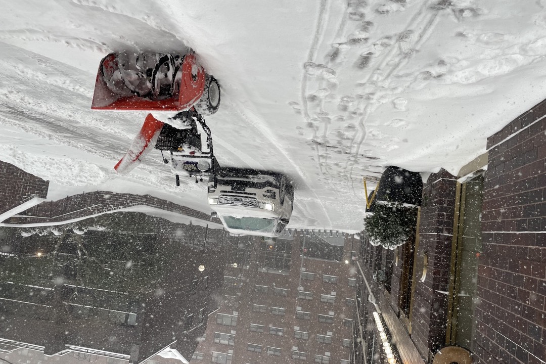 Ariens snow blower clearing a driveway during a winter snowstorm