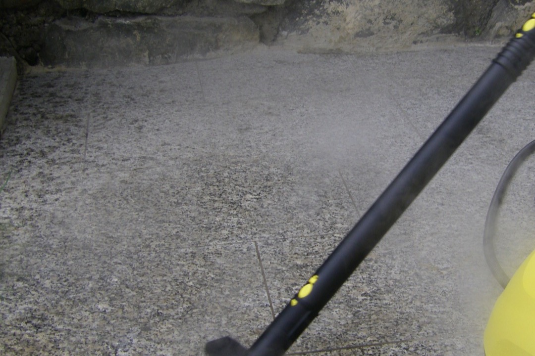 Upright steam mop cleaning a sealed tile kitchen floor with visible vapor