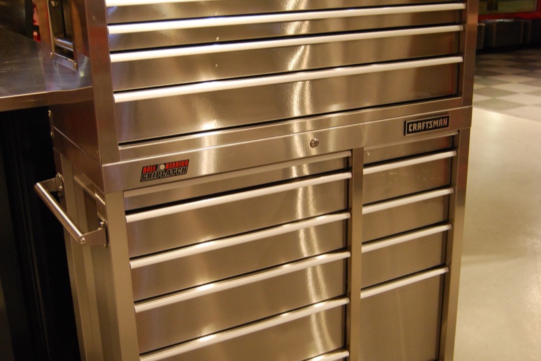 Rolling steel tool chest with multiple drawers open showing organized hand tools and sockets