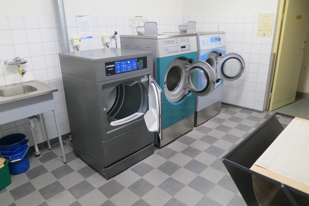 Rows of residential washing machines in a shared condominium laundry room