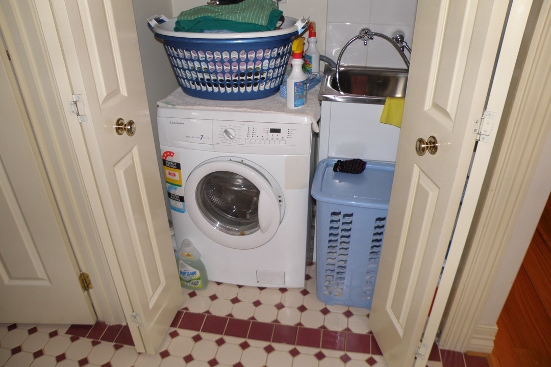White washer dryer combo unit installed in a compact laundry closet