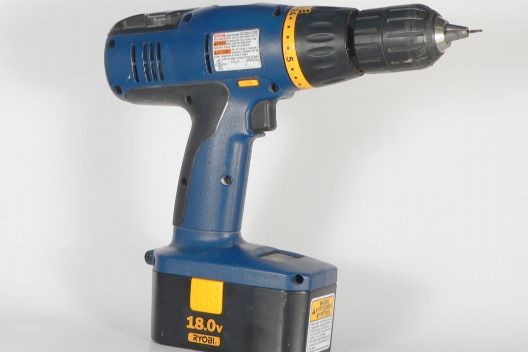 Cordless drill driver on a workshop bench next to woodworking project