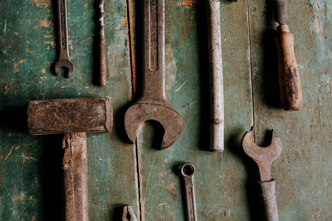 A homeowner's hand-tool kit laid out on a workbench next to a clipboard with a contractor estimate, illustrating the DIY-versus-hire decision discussed in this guide