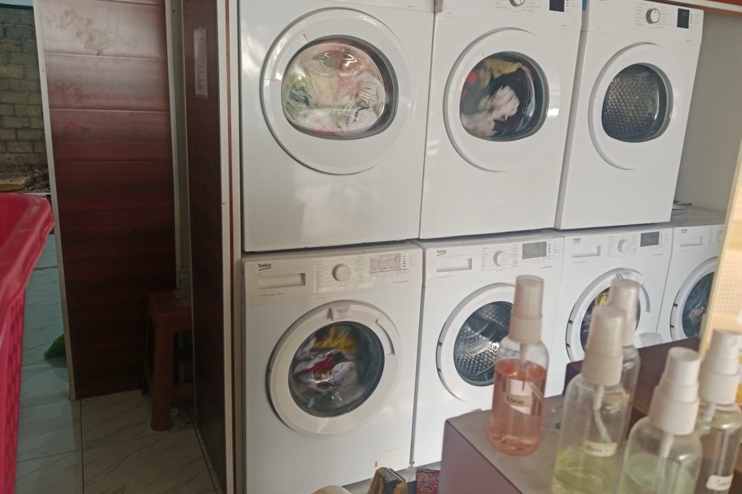 Multiple washing machines displayed in a laundry shop showing front-load and top-load models side by side