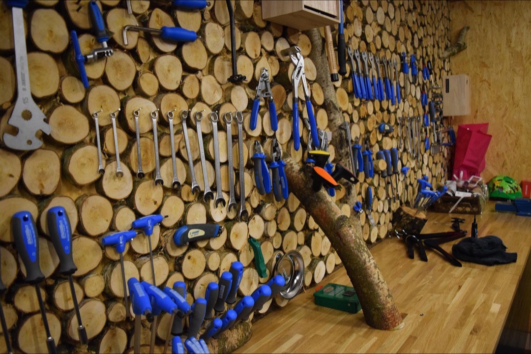 A workshop wall with wrenches, screwdrivers, and pliers hung in neat rows on a wall-mounted tool rack, illustrating vertical garage organization