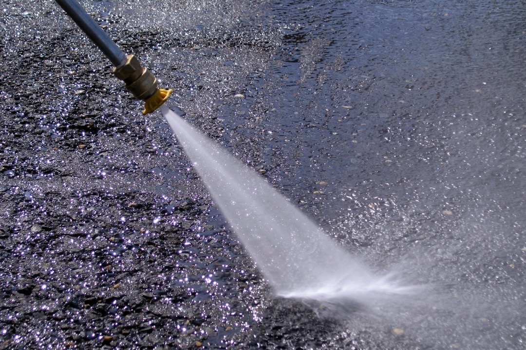 Pressure washer being used to clean a concrete driveway surface