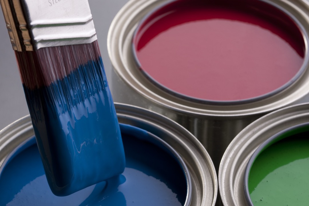 Open paint cans with mixed colors arranged on a workshop floor
