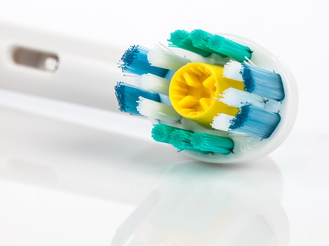 Close-up of an electric toothbrush head with white and blue bristles